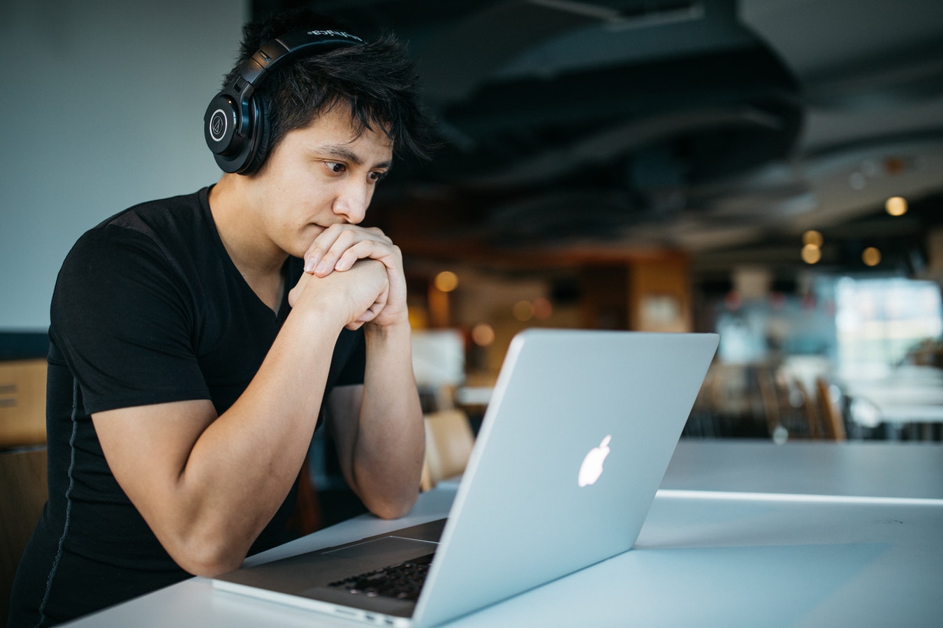 Man looking worried at a apple laptop screen in a cafe